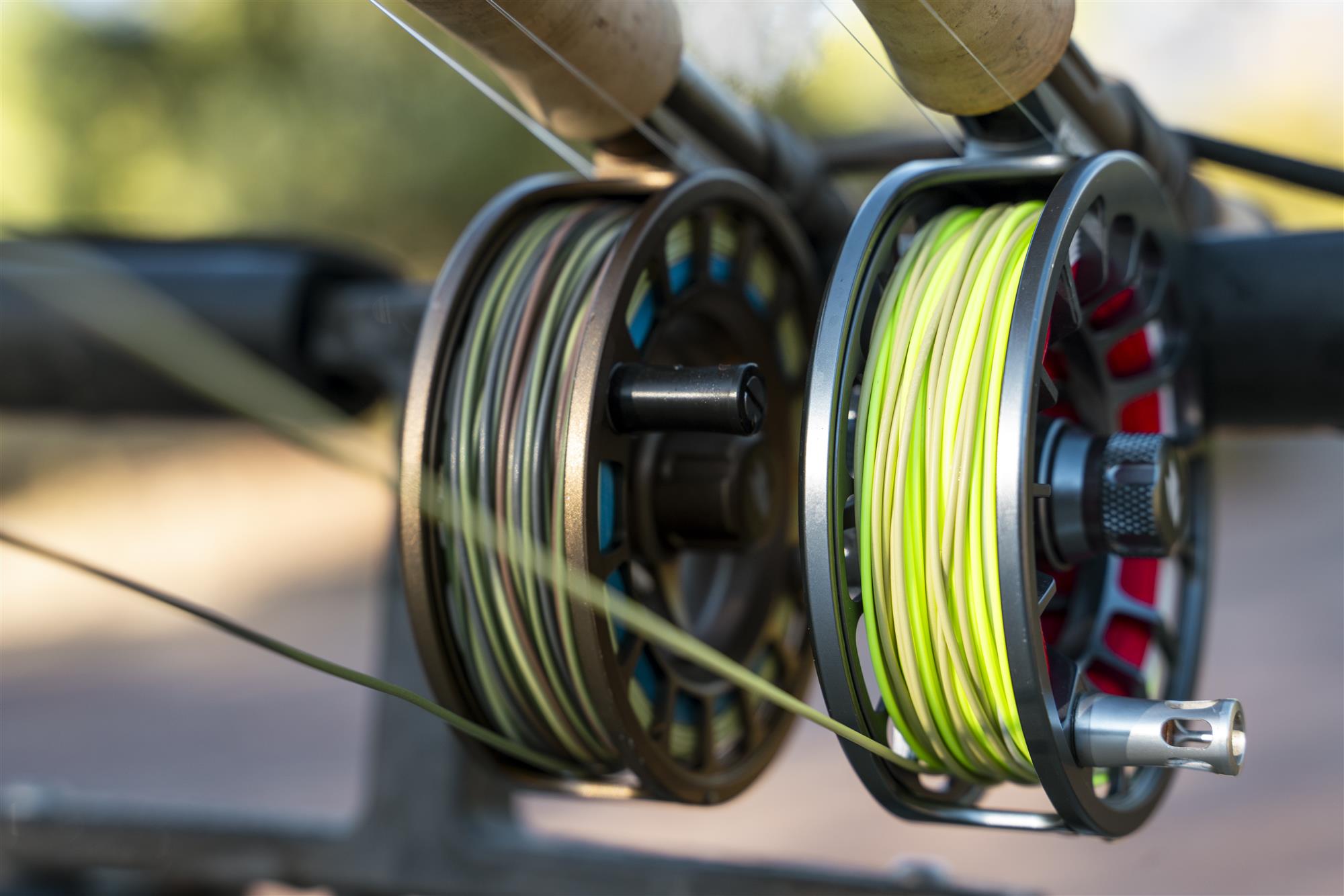 Sage SHIFT fly fishing reel shown alongside another fly reel on a rod rack, spooled with fly line and backing