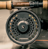 Sage SPEY 2 Reel mounted on a spey rod, set against a backdrop of lush greenery, ideal for salmon and steelhead fishing.