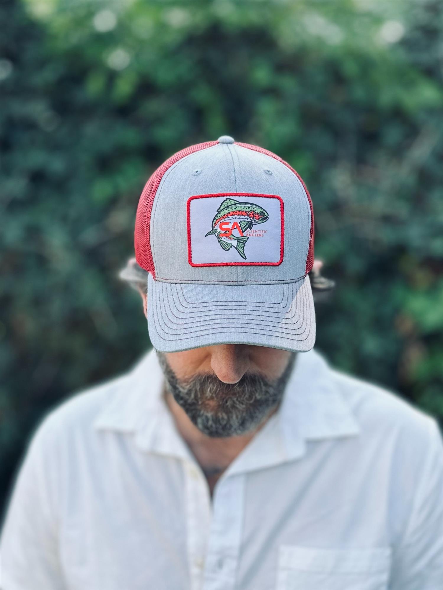 Scientific Anglers Rainbow Trout Patch Trucker Hat worn outdoors with rainbow trout fishing patch