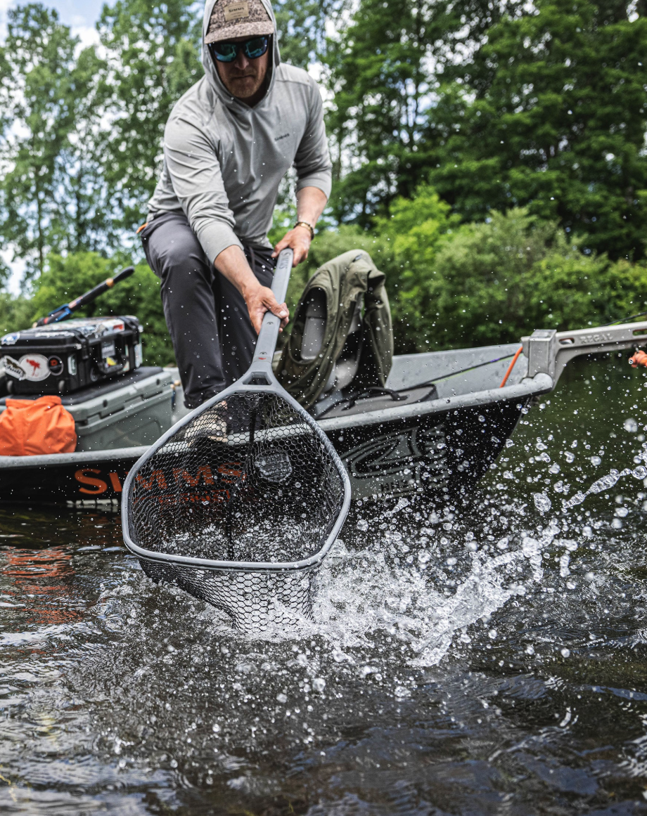 Angler landing fish from boat with Simms Daymaker Boat Net Long Handle