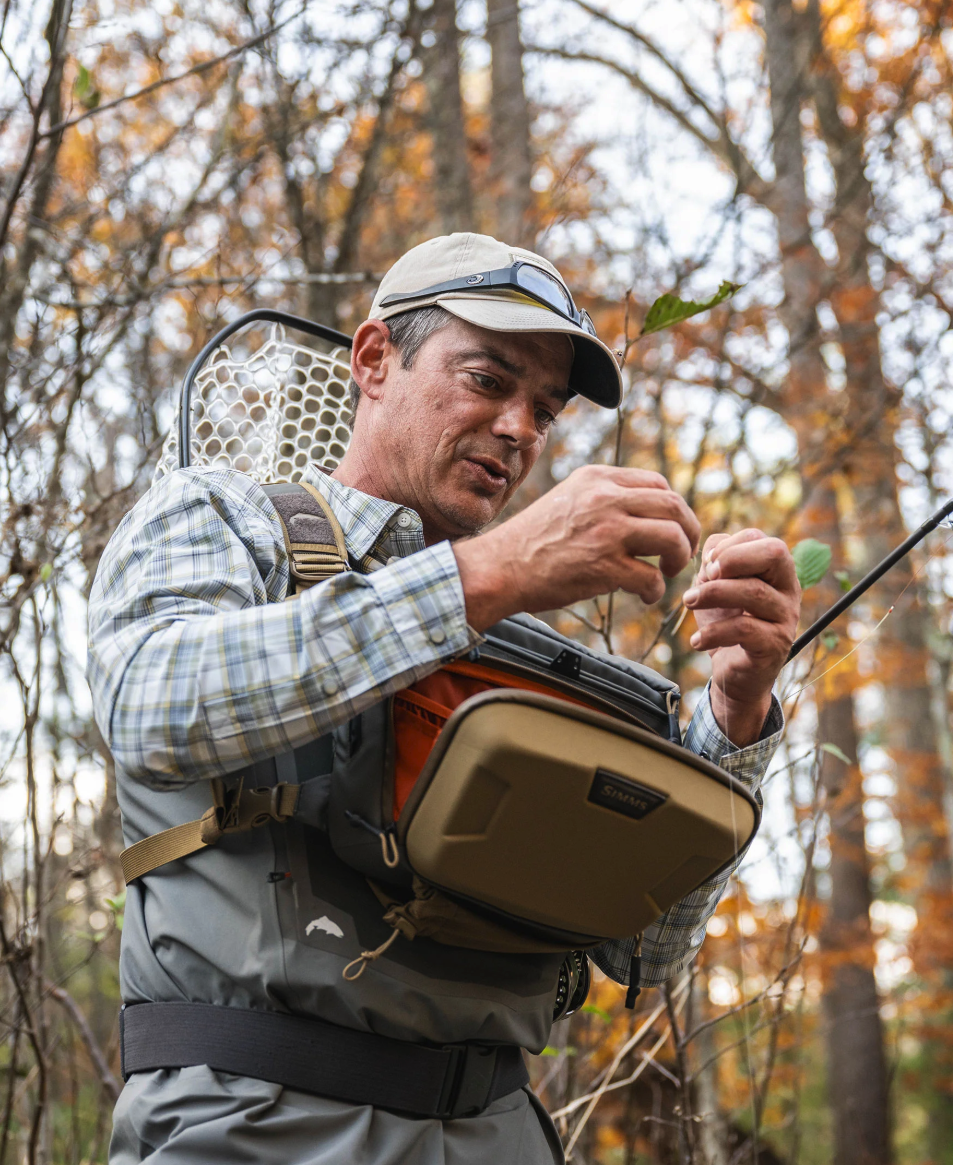 Angler using the front of the Simms Headwaters Chest Pack while fishing.