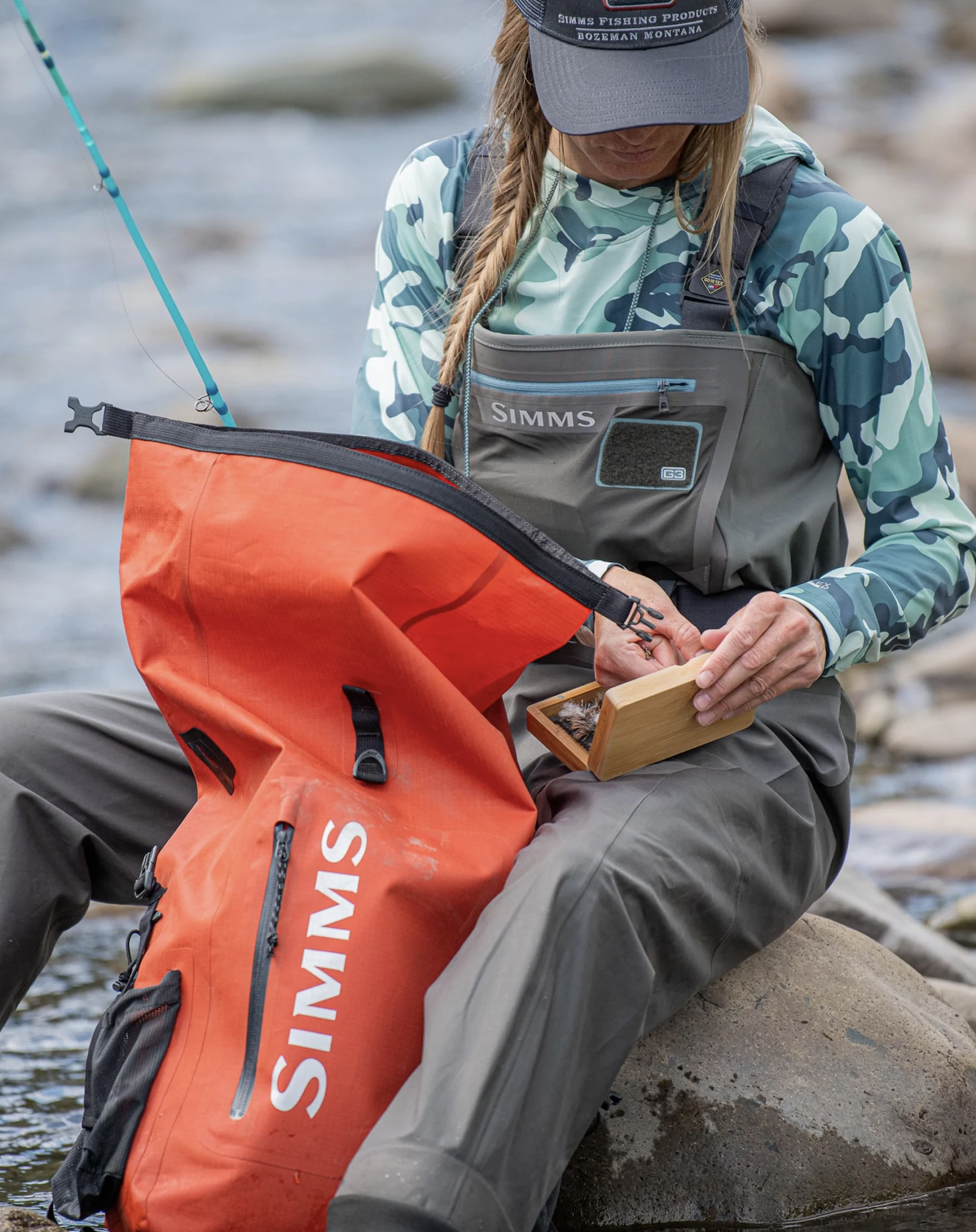 Waterproof Simms fishing backpack with roll-top closure for added protection.