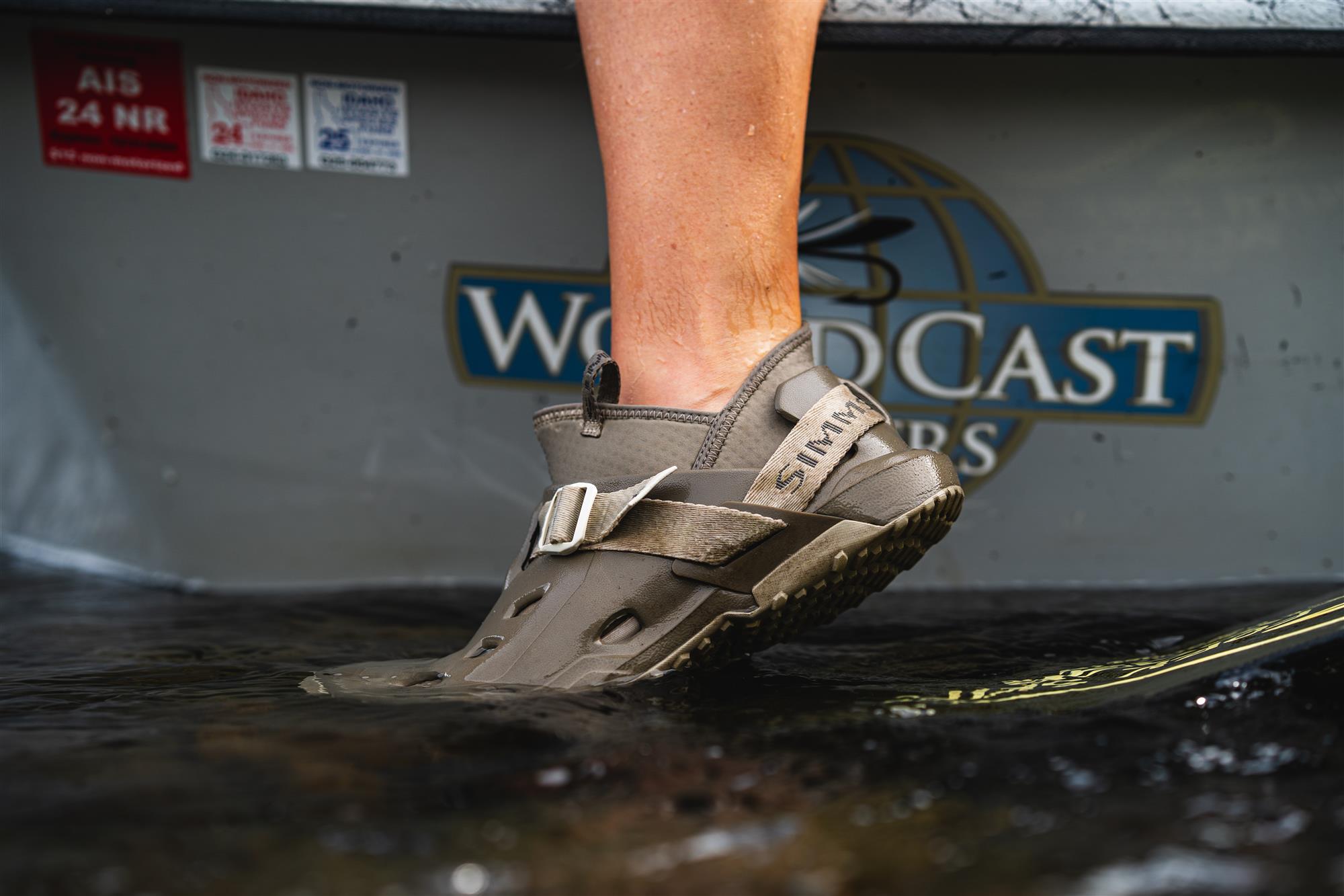 Angler stepping out of drift boat wearing Simms Drifter AT wet wading shoes for traction and quick-drain comfort