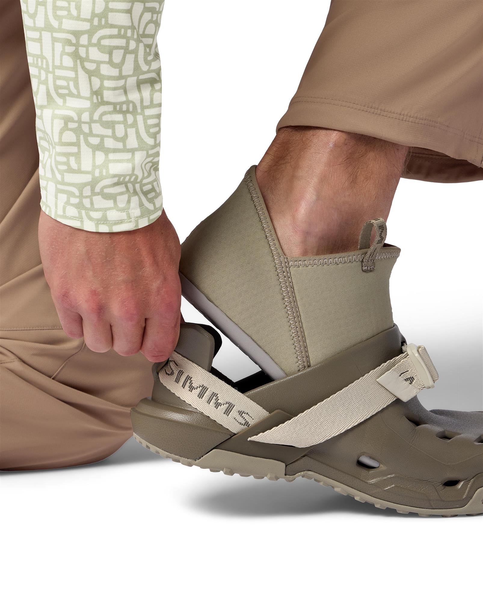 Putting on Simms Drifter AT fishing water shoe with adjustable webbing strap and quick-drain wet wading design