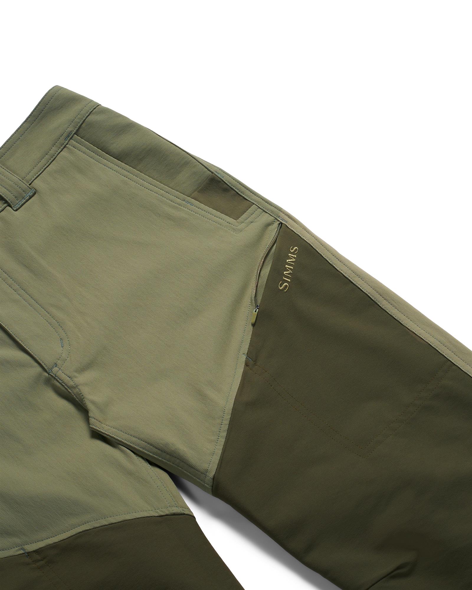Simms technical outdoor pants close-up showing reinforced knee overlay and secure thigh storage