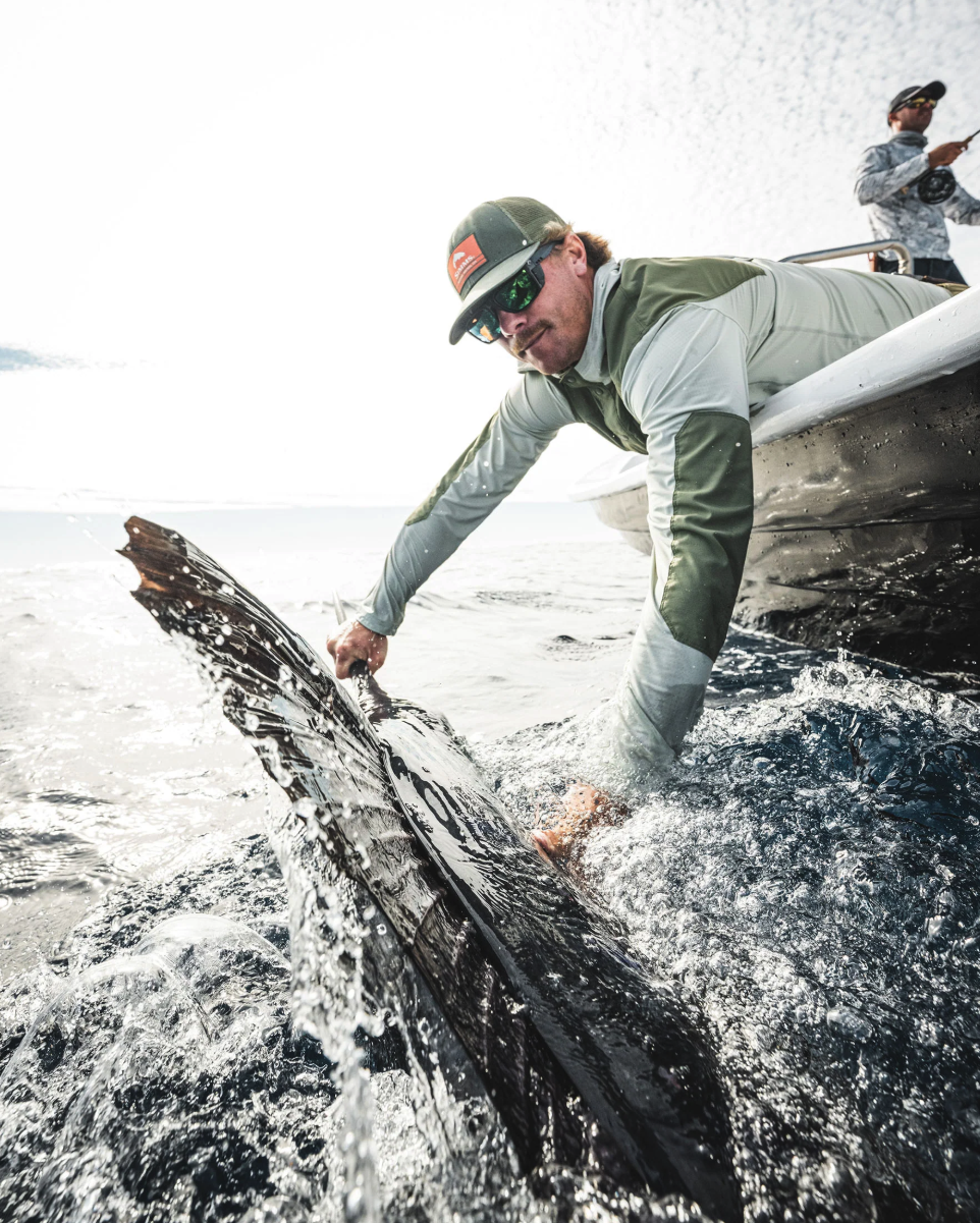 Angler landing sailfish next to a boat