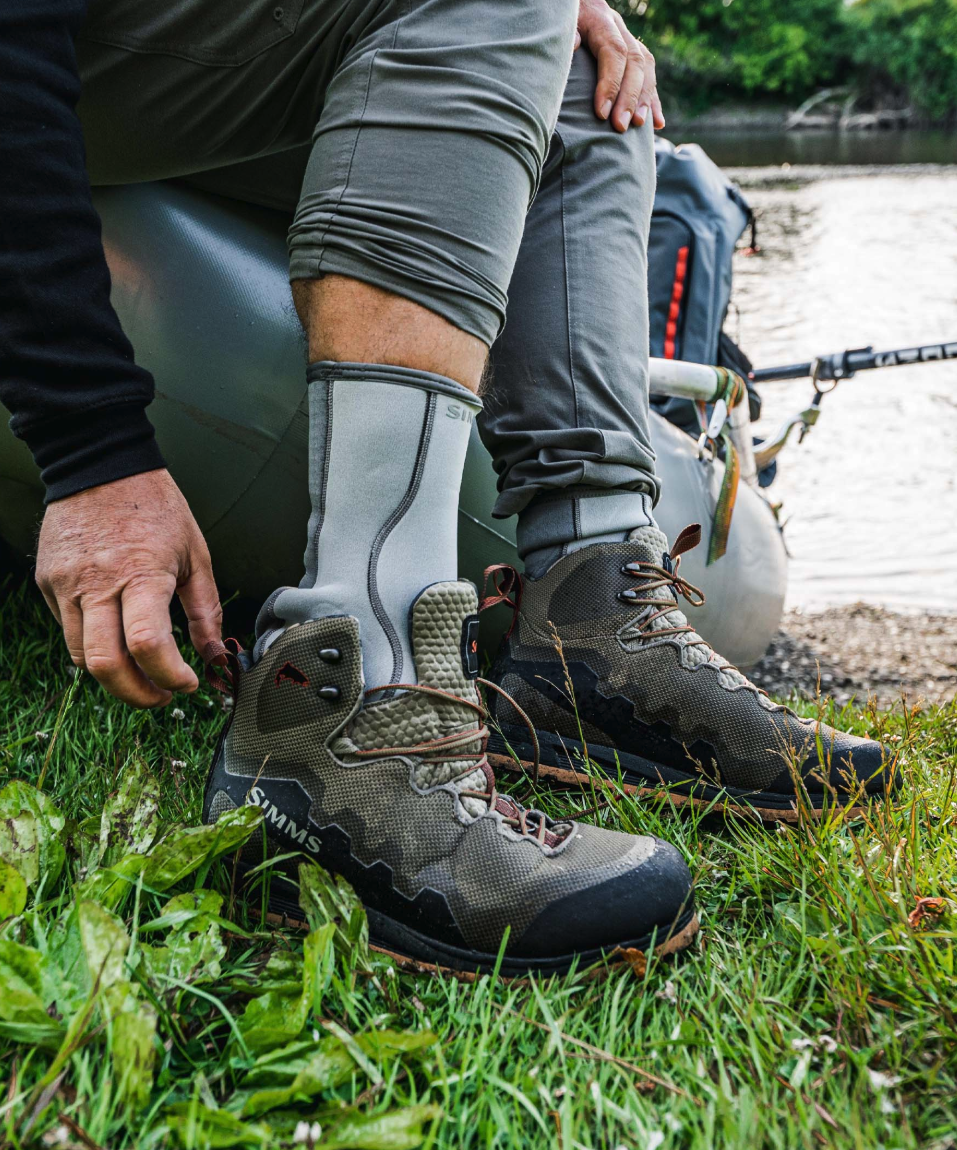 Angler putting on Simms Neoprene Wading Socks.