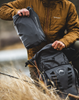 Man putting Simms Flyweight Packable Waders in backpack