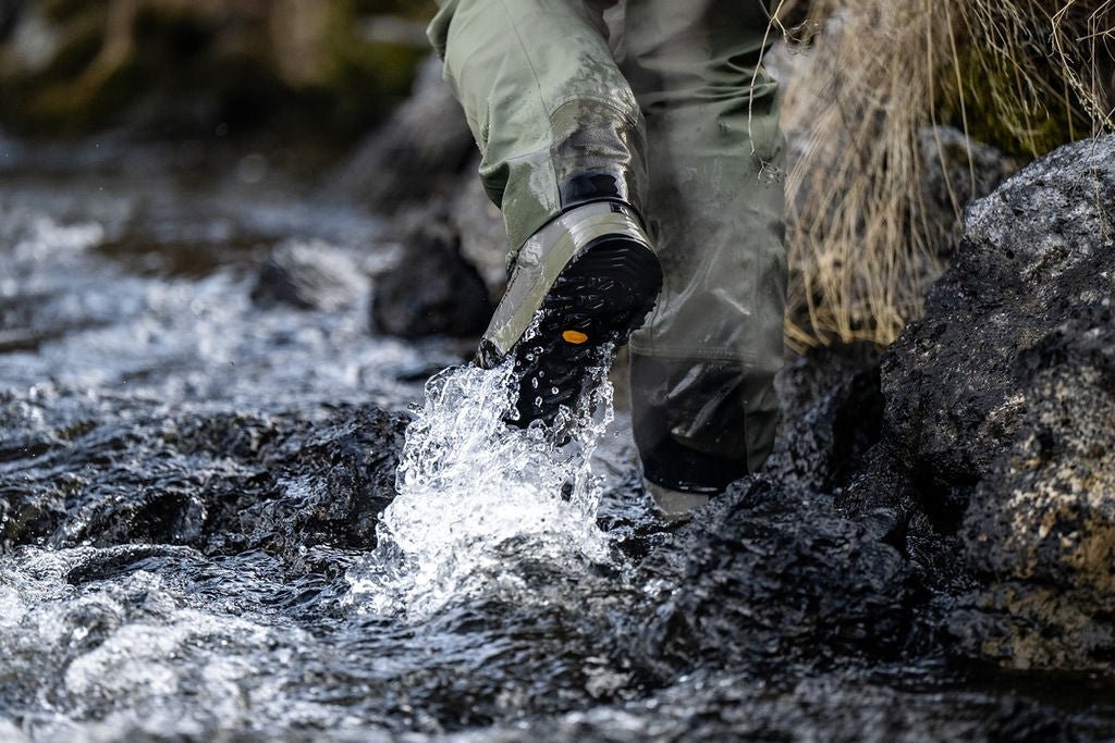 Fly angler wearing Skwala Carbon Wading Boots stepping across rocky river terrain with superior Vibram traction