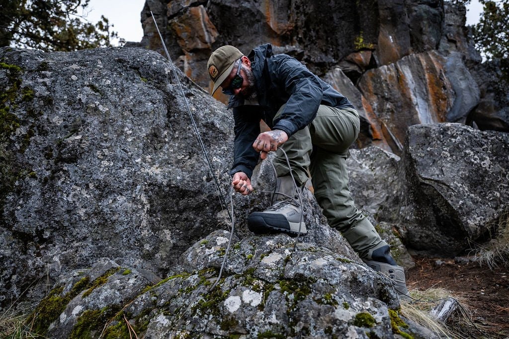 Fly fisherman tightening Skwala Carbon Wading Boots with secure lace system before hiking to remote trout water
