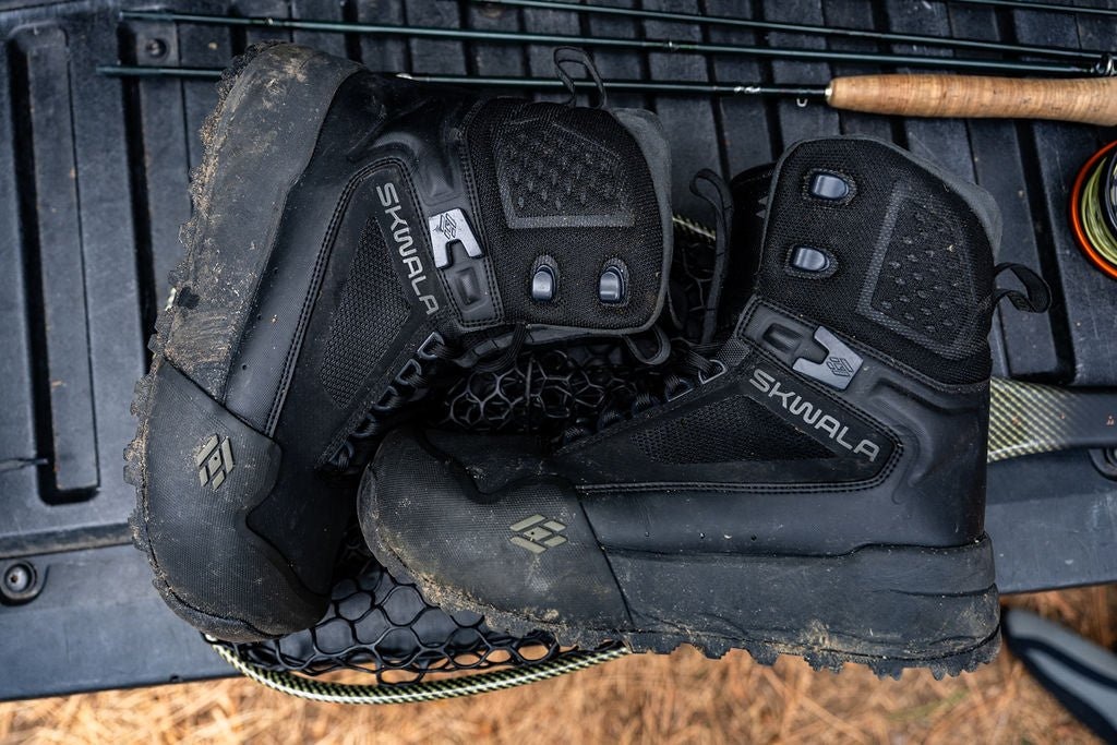 Pair of Skwala RS fly fishing wading boots resting on tailgate with fishing gear and landing net