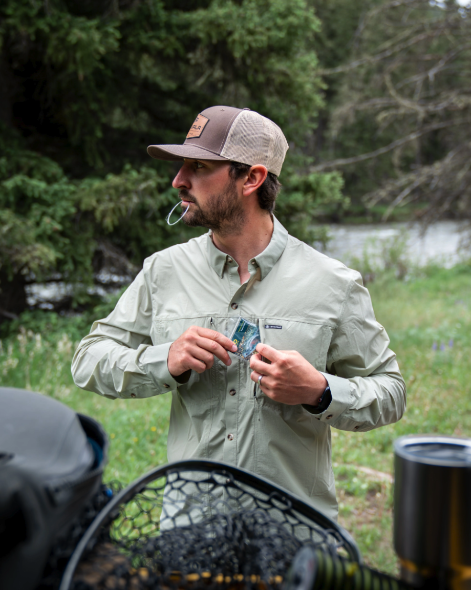 Angler putting sunglasses in pocket of Skwala Sol Breeze Shirt