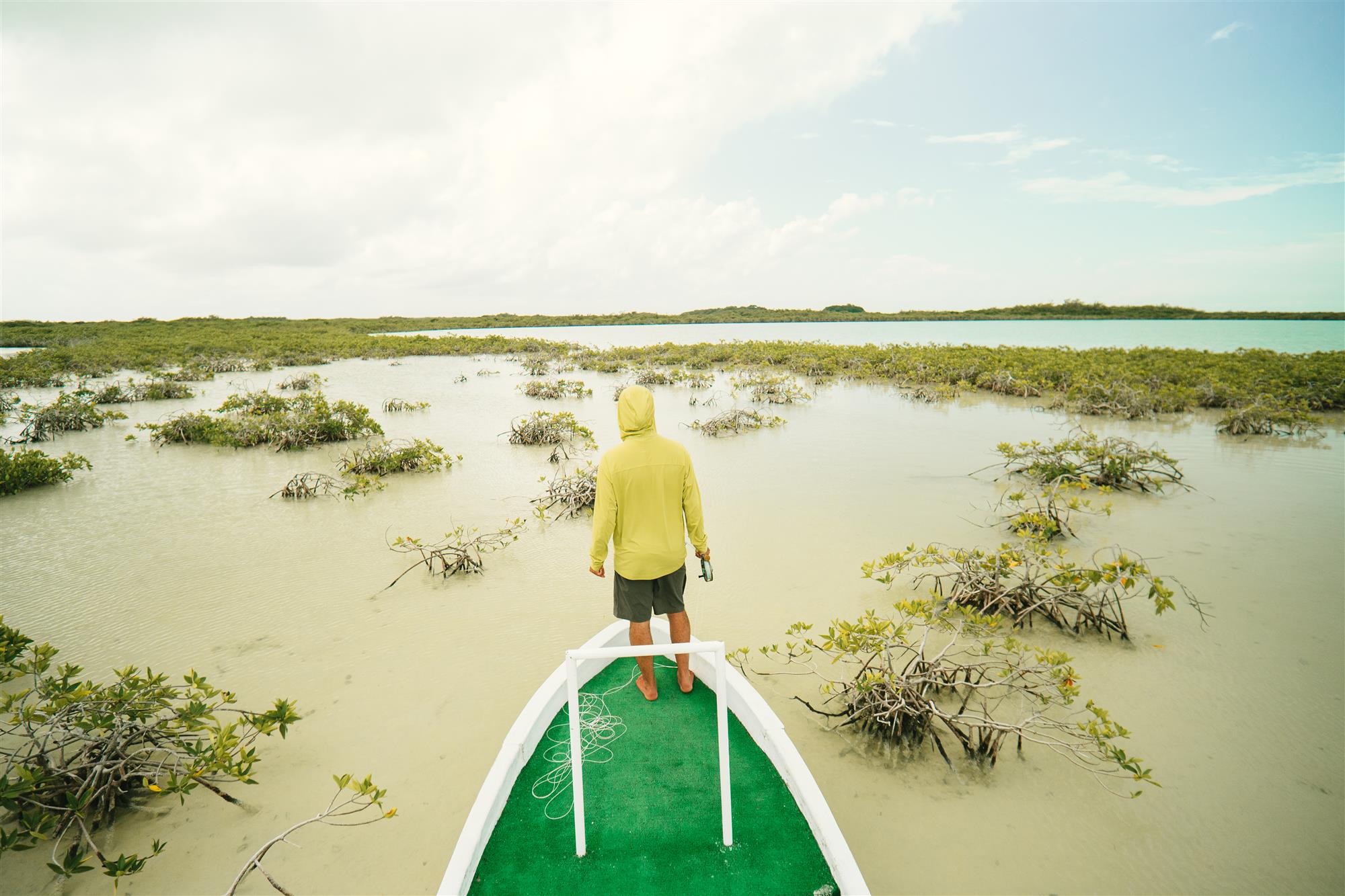 Skwala Sol Defense Hoody worn while sight fishing from boat in tropical flats and mangrove water