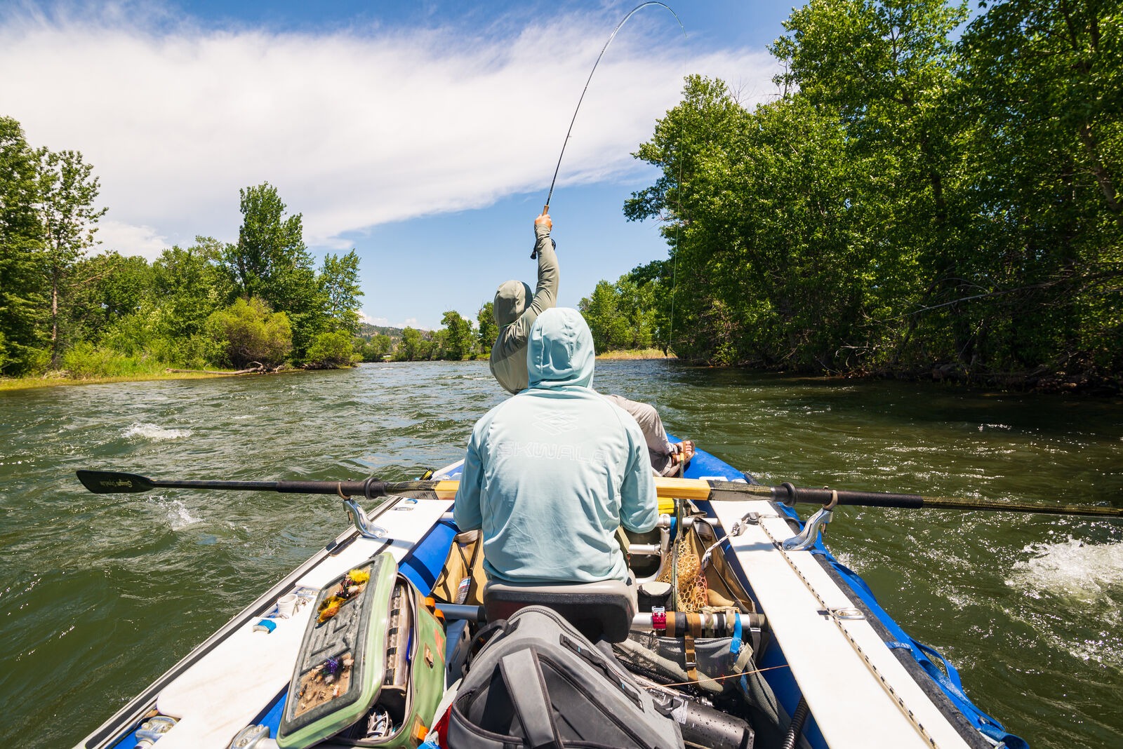 Angler wearing Skwala Sol Tropic Sun Hoody breathable UPF fishing shirt while fly fishing from drift boat