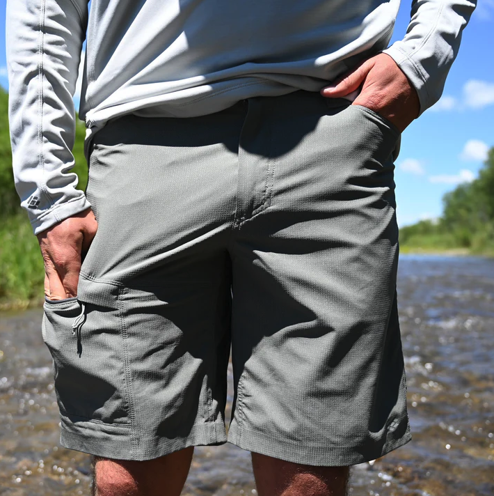 Front of angler wearing Skwala Sol Shorts Charcoal color standing in river
