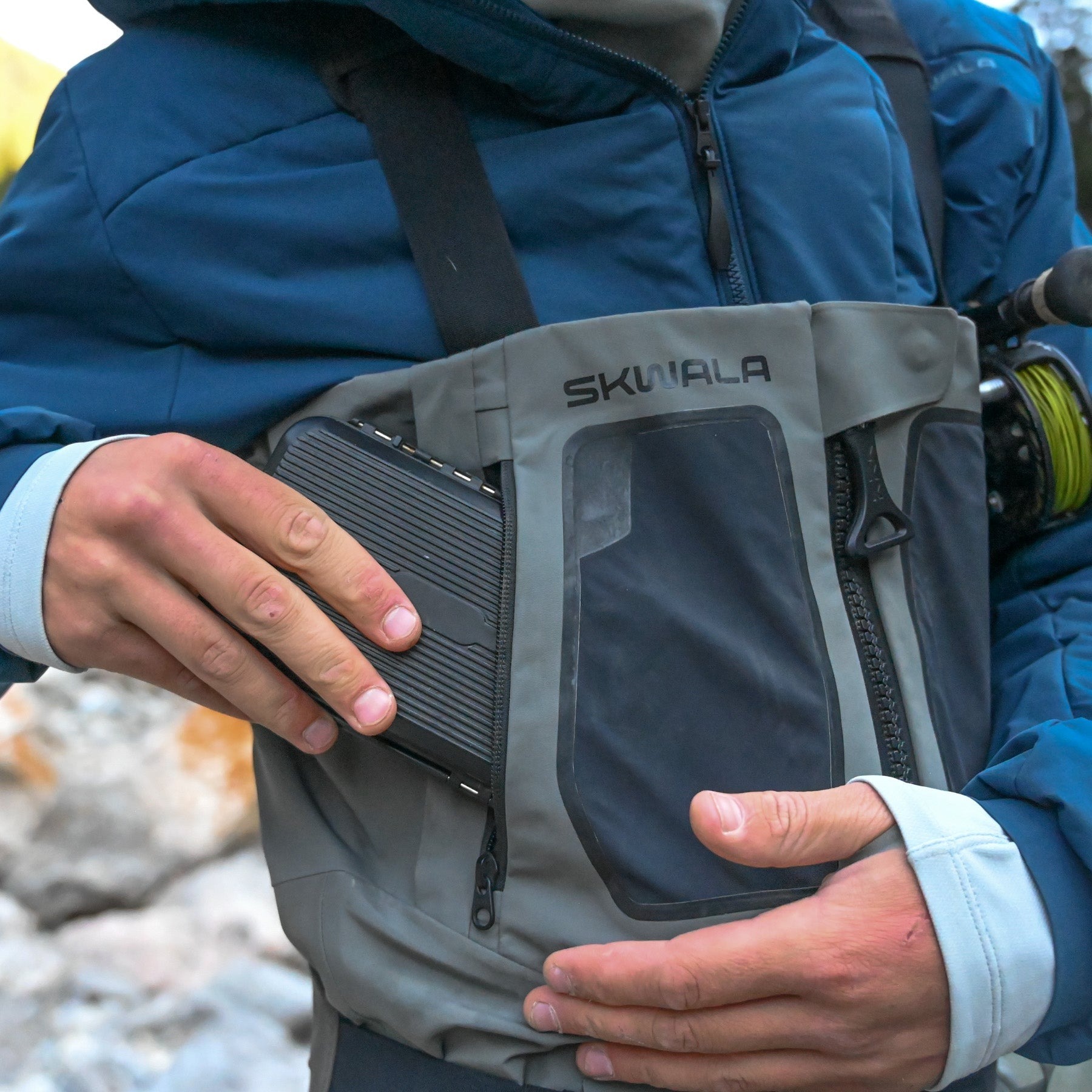 Angler storing fly box in chest pocket of Skwala RS Zip Front waterproof breathable fly fishing waders