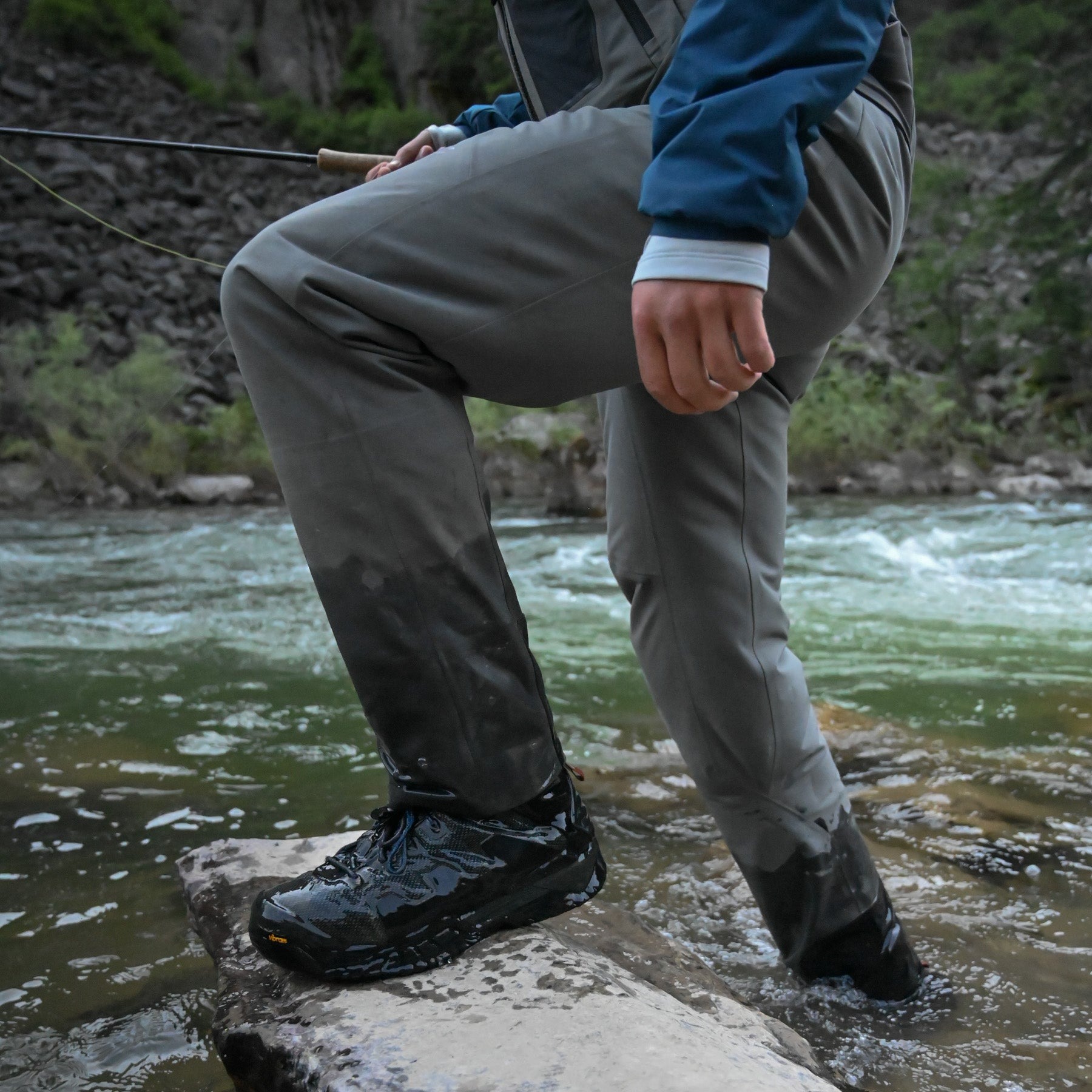 Skwala RS Zip Front fly fishing waders stepping on river rock while wading in fast moving trout stream