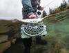 Fly fisherman holding Turtlebox Original Speaker in water.