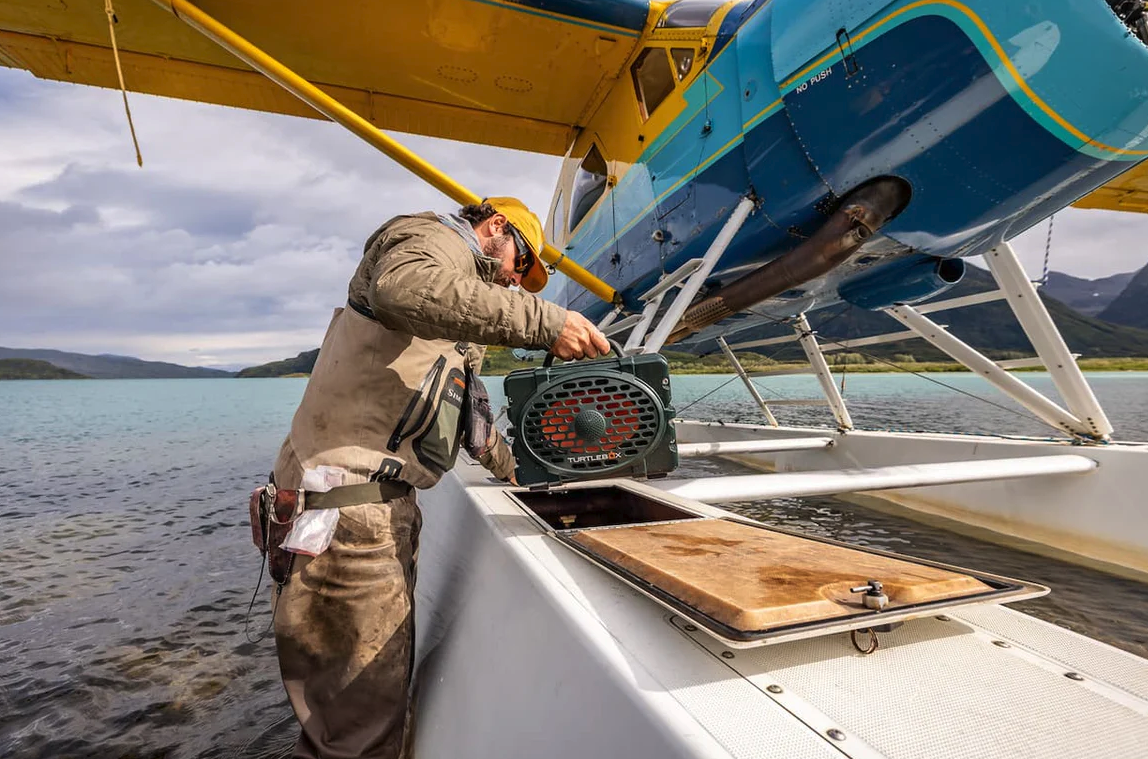 Man putting Turtlebox Original Speaker into float plane