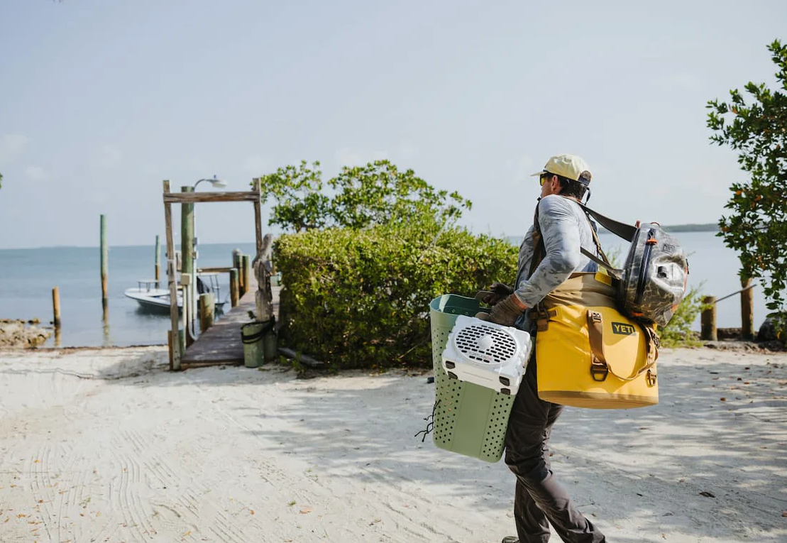 Fly angler carrying Turtlebox Original Speaker to flats boat