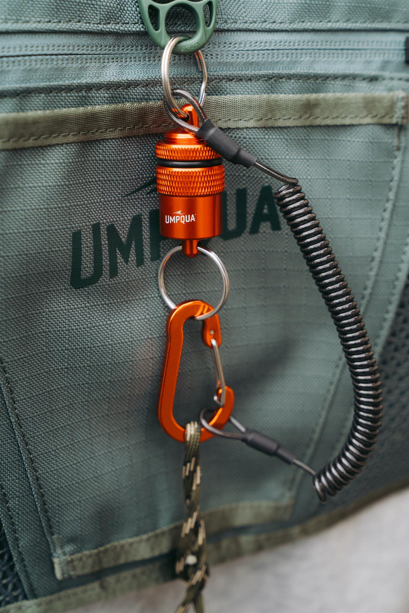 Orange Umpqua RiverRun Magnetic Net Release attached to a fly fishing pack with carabiner clip and expandable coil tether