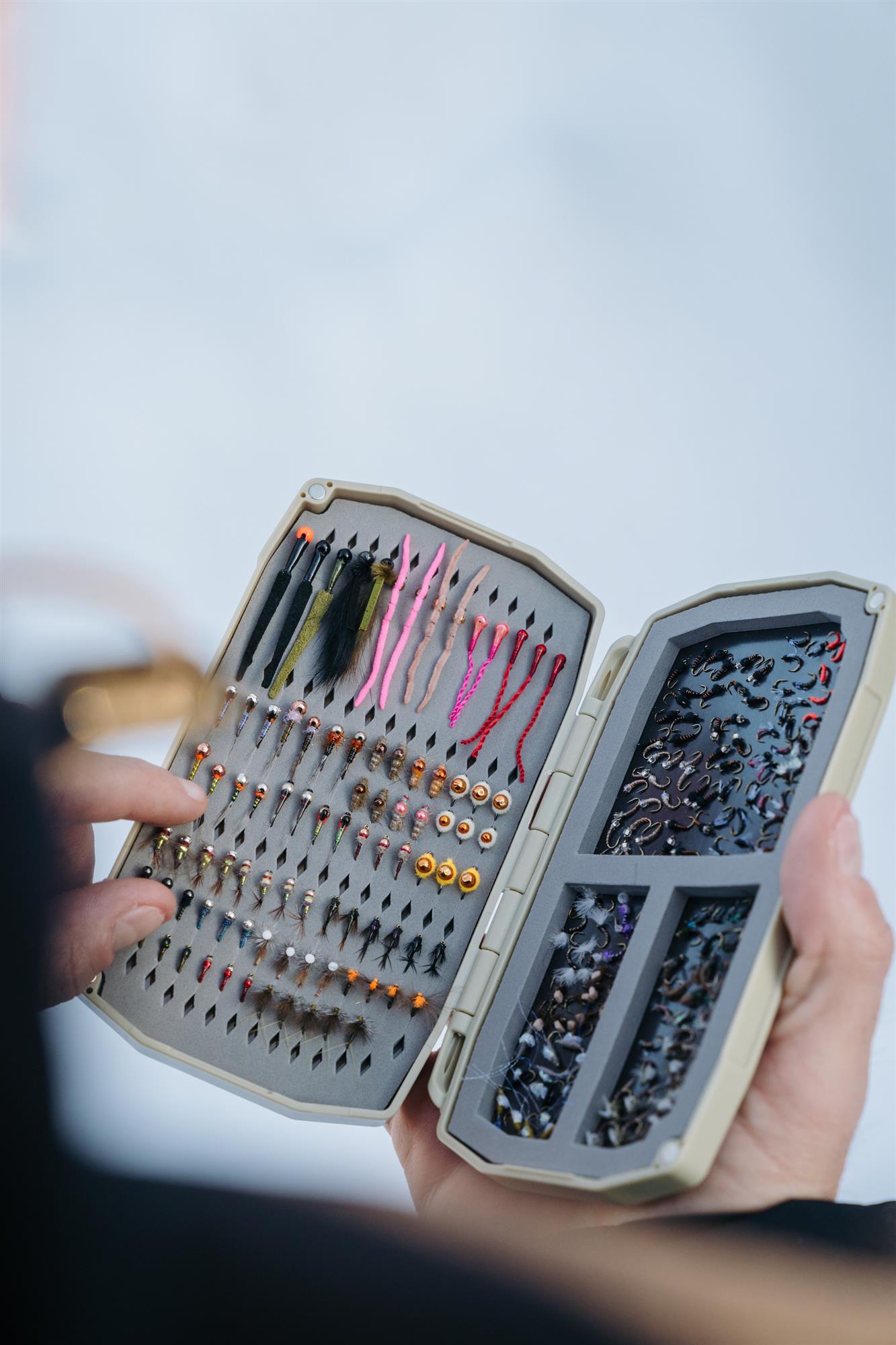An angler picking a fly out of an Umpqua UPG Tailwater Fly Box