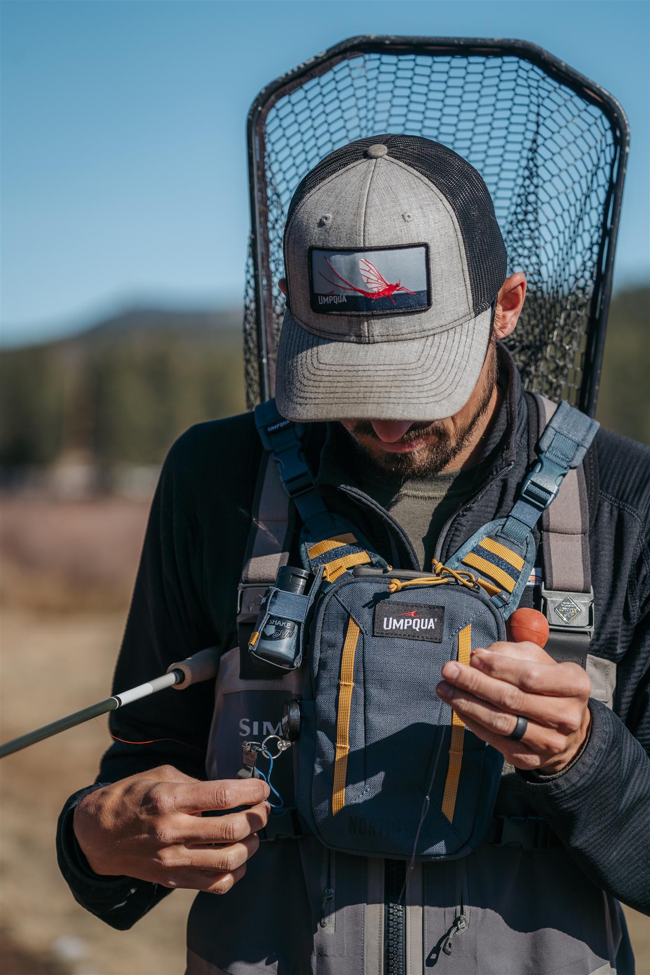 Angler prepping tippet while wearing the Umpqua North Fork Small Chest Pack