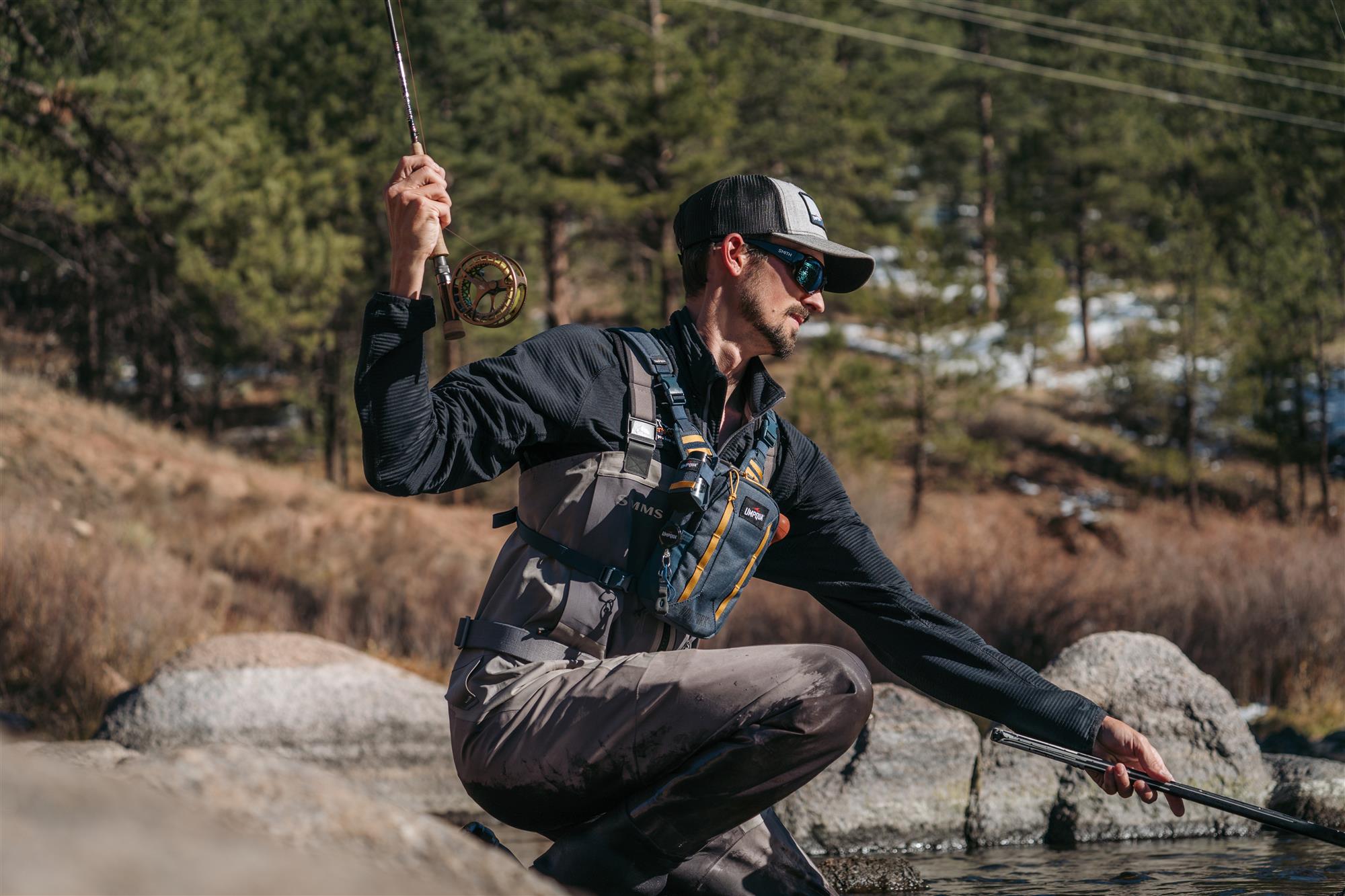 Angler netting a fish while wearing the Umpqua North Fork Small Chest Pack