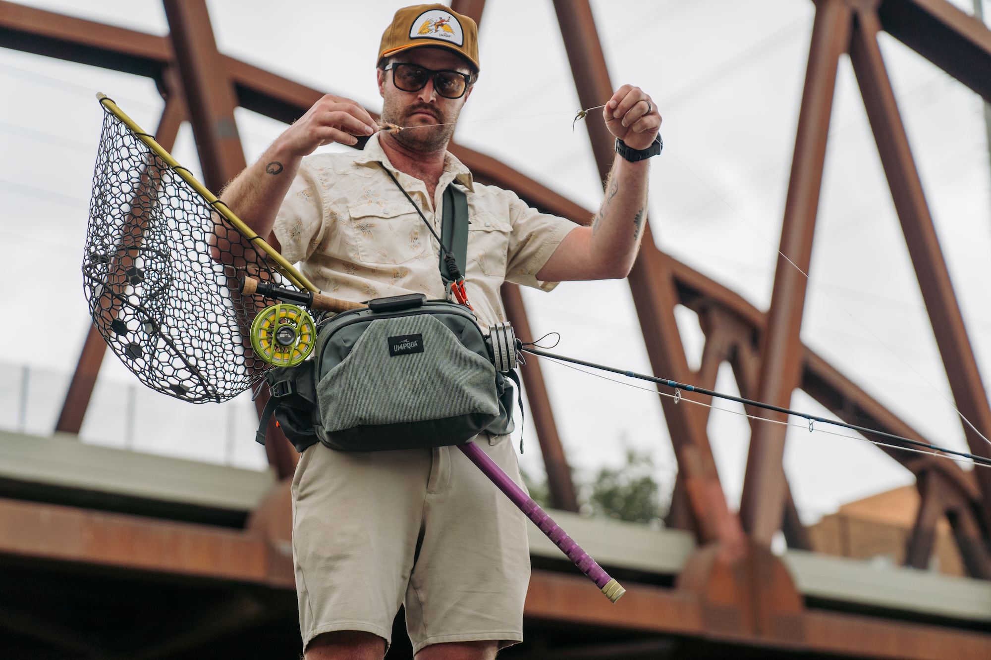 Fly fisherman rigging leader with Umpqua Ledges waist pack chest worn modular fishing pack with net and fly rod