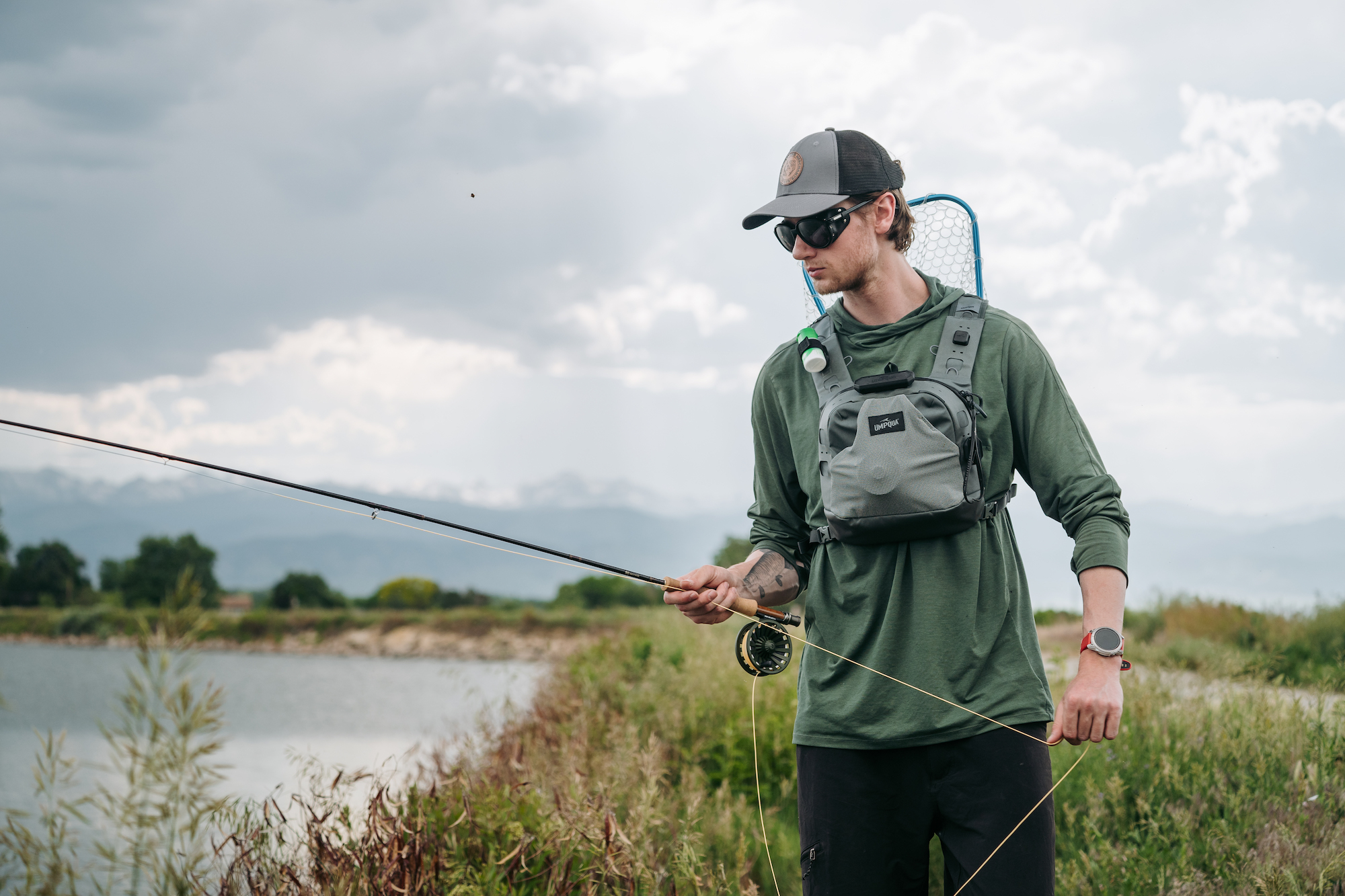 Fly fisherman wearing chest pack casting rod Umpqua SWIFTLINK ThunderCreek on river bank