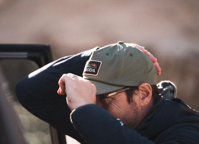 Man wearing and adjusting Yakoda Great Outdoors Hat Spruce