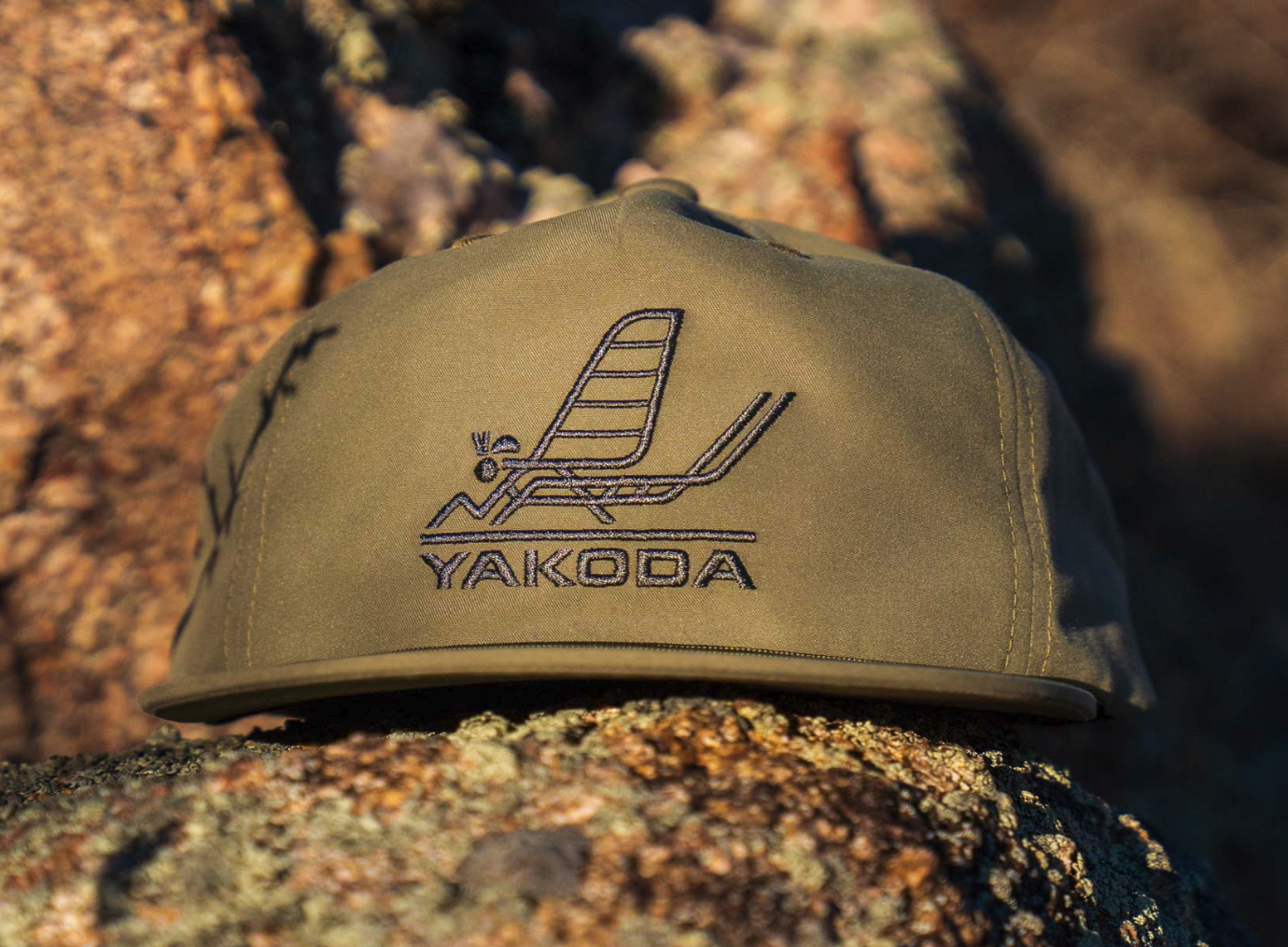 Yakoda Mayfly Hat in sage color on a rock ledge.