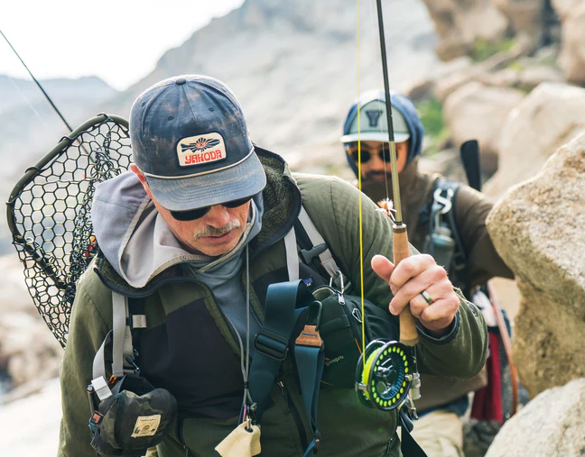 Angler wearing Yakoda Mystic Trout Hat Midnight and holding fly rod